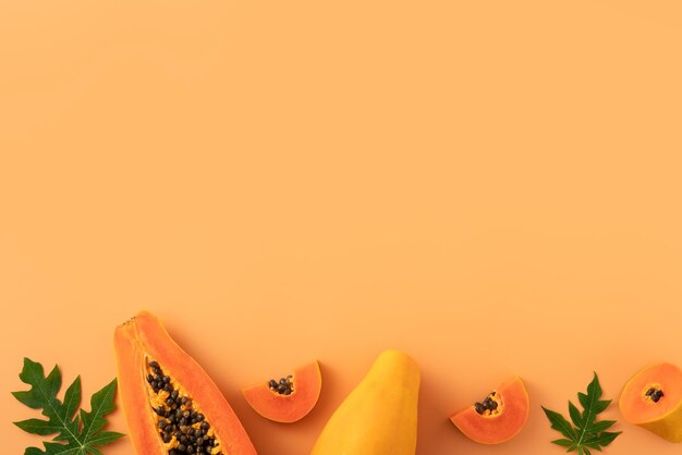 Foto snijd papaya over oranje tafelachtergrond voor tropisch fruit ontwerp concept bovenaanzicht kopie ruimte