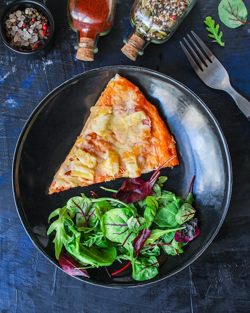 Snijd pizza en salade bladeren in een bord op tafel