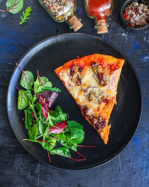 snijd pizza en salade bladeren in een bord op tafel