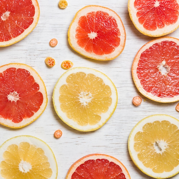 Foto snijd rode en gele grapefruit en kleine citrussnoepjes op een witte houten ondergrond sappig en vers