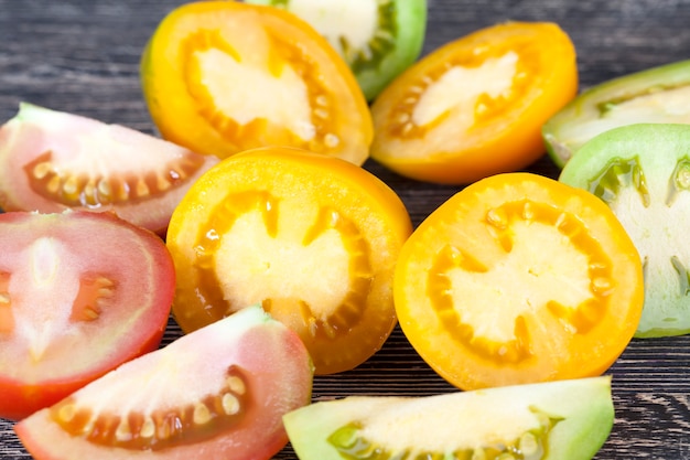 Snijd tijdens het koken rode, gele en groene tomaten, close-up in de keuken