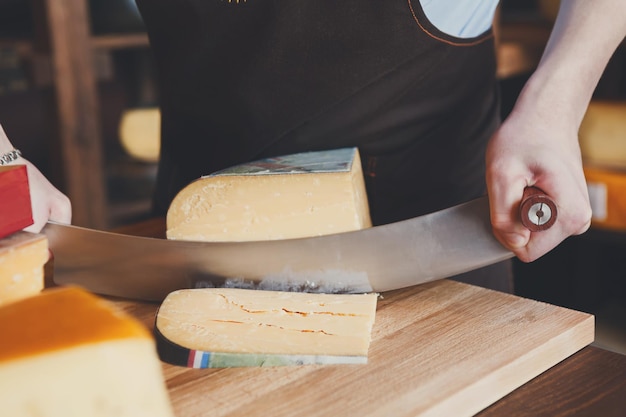 Snijden van harde kaas, pecorino-kaas in de kruidenierswinkel, close-up