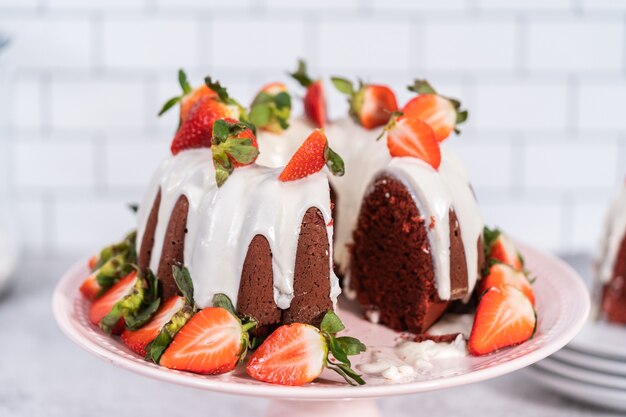 Snijden van red velvet bundt cake met roomkaas frosting gegarneerd met verse aardbeien.