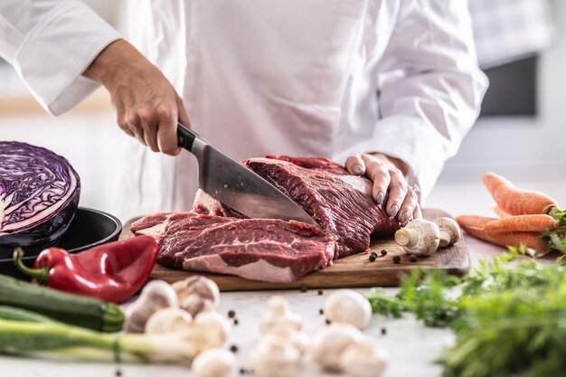 Snijden van rundvlees of varkensvlees brok met mes in een professionele restaurantkeuken.