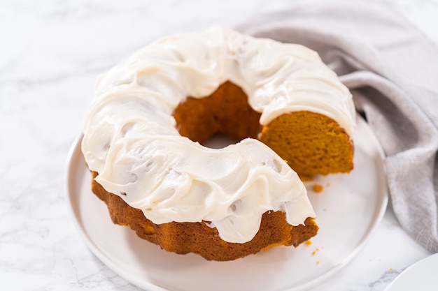 Snijden van zelfgemaakte pompoen bunt cake met roomkaas frosting.