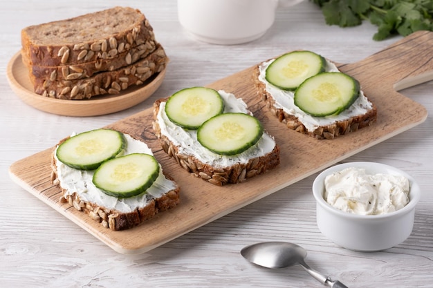 Snijden volkorenbrood met roomkaas en verse komkommer, prachtig gerangschikt op een