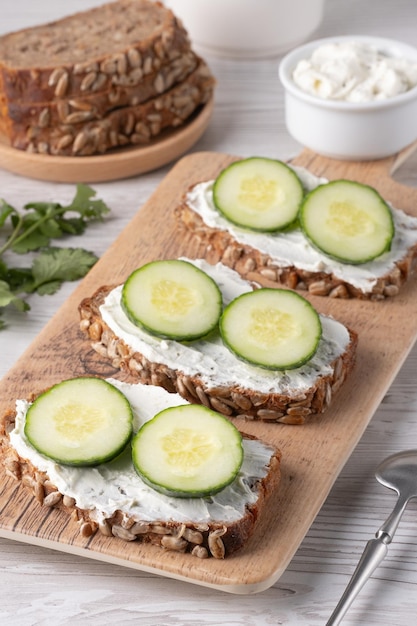 Snijden volkorenbrood met roomkaas en verse komkommer, prachtig gerangschikt op een