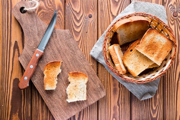 Snijplank met een mes en een mand met toast op een houten