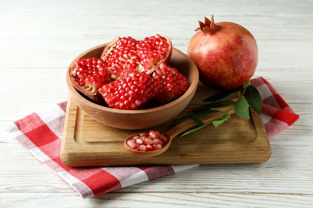 Snijplank met granaatappel op witte houten tafel