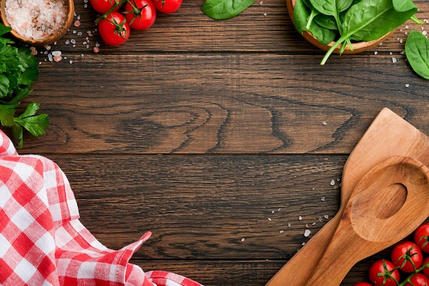 Snijplank met keukenlepels en rood servet en peterselietomaat om te koken op oude houten donkere achtergrond Vegetarisch voedsel gezondheid of kookconcept Voedsel achtergrond met vrije ruimte voor tekst