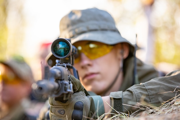 Sniper armed with large caliber, sniper rifle, shooting enemy targets on range from shelter, sitting in ambush