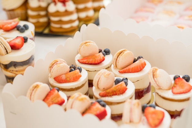 Snoepjes en een chocoladetaart op een dessert tafel op feestje. cake met verschillende bessen en schuimgebakjes op een standaard. cakes, dessert met bessen, snoepreep voor feest