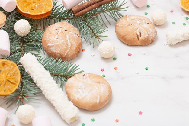 Snoepjes en koekjes met kerstboomtakken op witte marmeren achtergrond