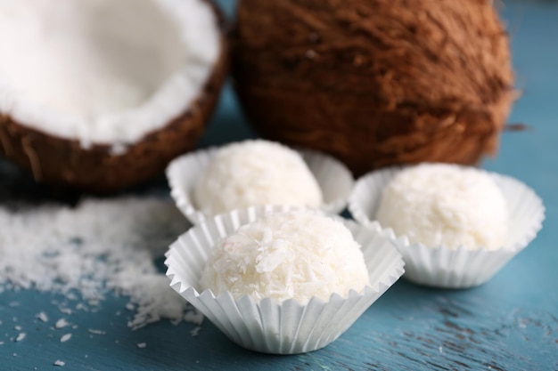 Snoepjes in kokosvlokken en verse kokosnoot op een houten achtergrond kleur