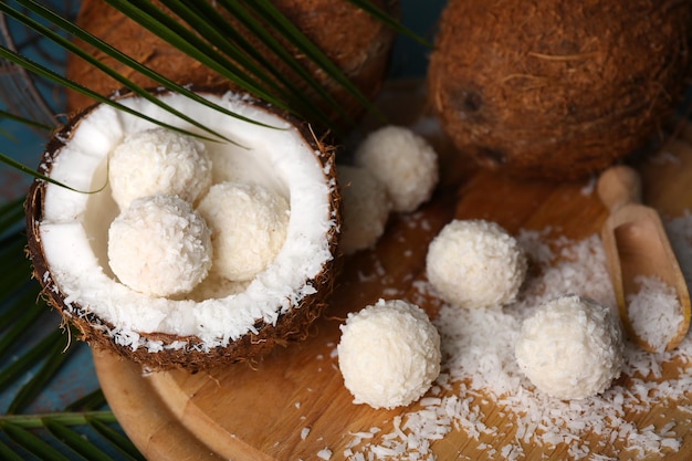 Snoepjes in kokosvlokken en verse kokosnoot op een houten achtergrond kleur