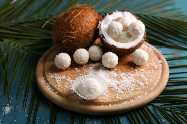 Snoepjes in kokosvlokken en verse kokosnoot op een houten achtergrond kleur