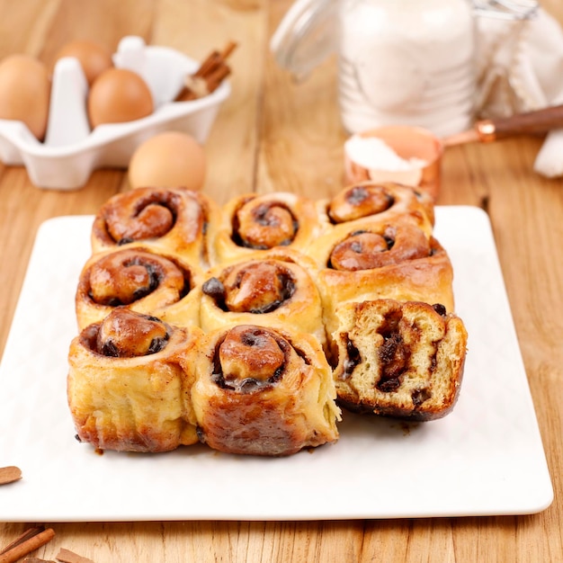 Snoepjes Kaneelbroodje met kaneelpoeder, half gesneden. Serveer op een wit bord