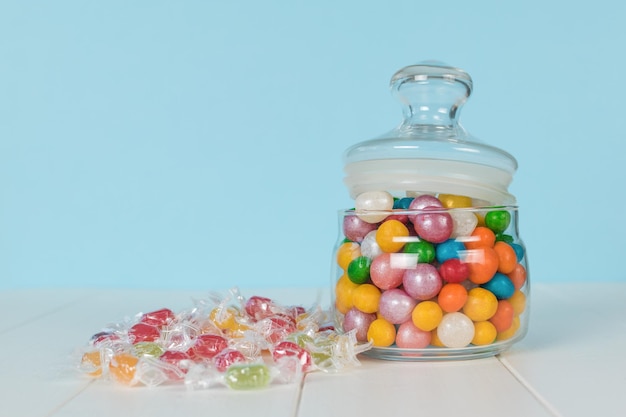 Snoepjes op een witte tafel en in een glazen pot Een traktatie voor het feest