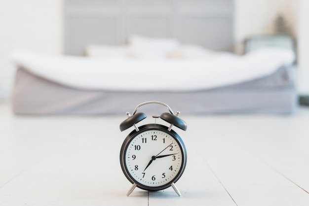 Foto snooze sul pavimento vicino al letto con lenzuola bianche