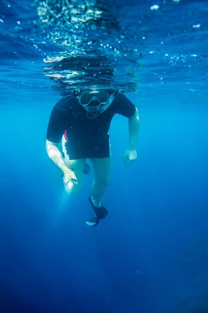 Snorkeler diving along the brain coral with flashlight