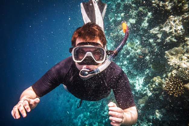 Фото Ныряльщик с маской и трубкой плавает под водой.