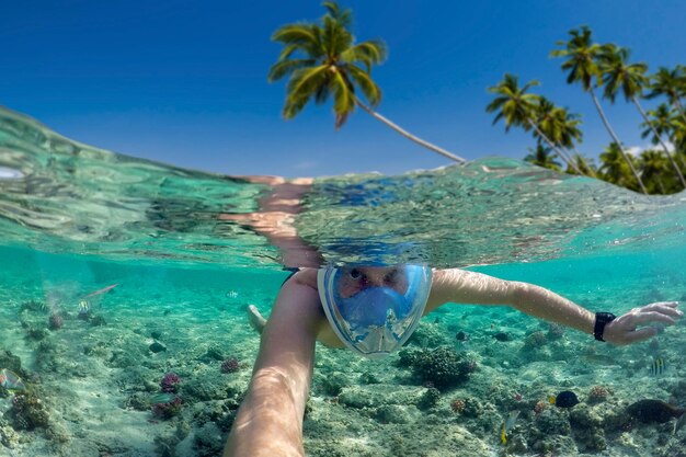Подводное плавание возле тропического острова Молодой человек плавает в воде Морской отдых