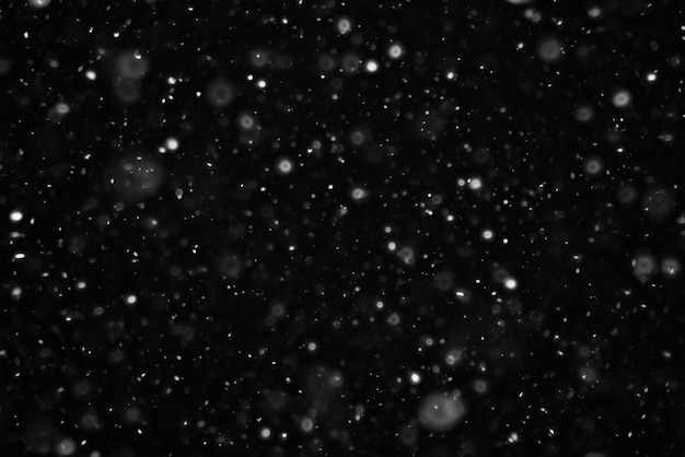 Foto neve su uno sfondo nero con sovrapposizione di texture bokeh punti salienti