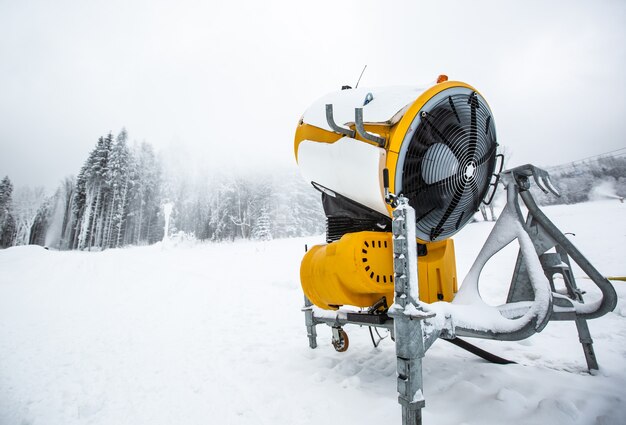 Cannone da neve, mitragliatrice o mitragliatrice che nevica sulle piste o in montagna per sciatori e snowboarder, neve artificiale