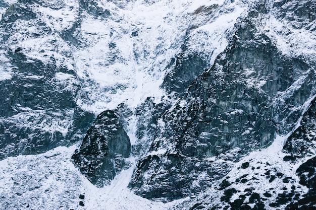 Primo piano innevato della montagna. la trama delle pietre nella neve