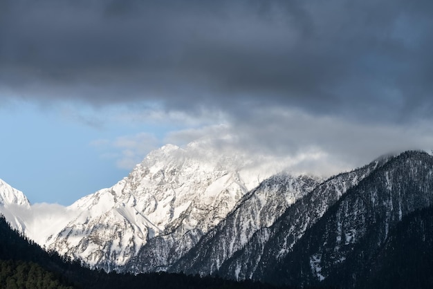 冬のチベットの雪をかぶった山と霧の雲高原の風景