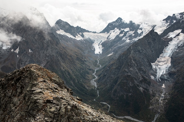 Snow capped mountain range in the clouds. Valley with a mountain stream. Caucasus, Russia