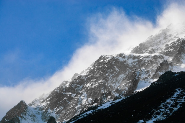 アルプスの雪をかぶった山々。山の頂上近くを飛ぶ雲