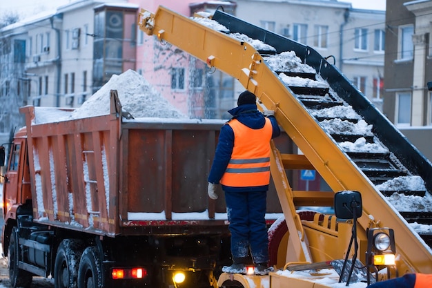 Snow cleaning tractor snowremoval machine loading pile of snow on a dump truck Isolate