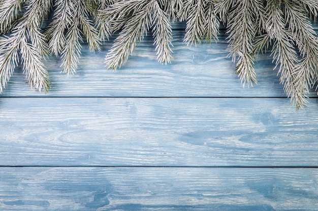 Snow-covered branches of spruce on a wooden background. Copy Space for text.