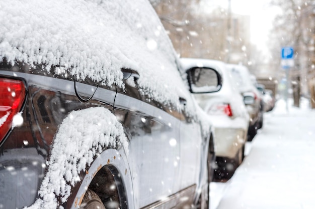 冬の駐車場に雪に覆われた車。側面図