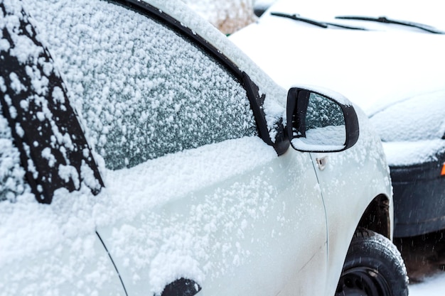 駐車場の雪に覆われた車。冬の都会のシーン