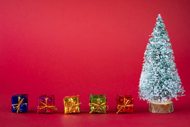 Snow-covered Christmas tree and bright multi-colored boxes with gifts.