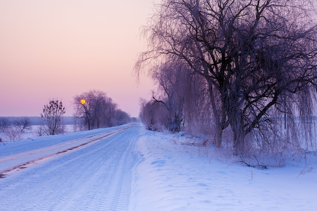 Snow covered country road at sunrise