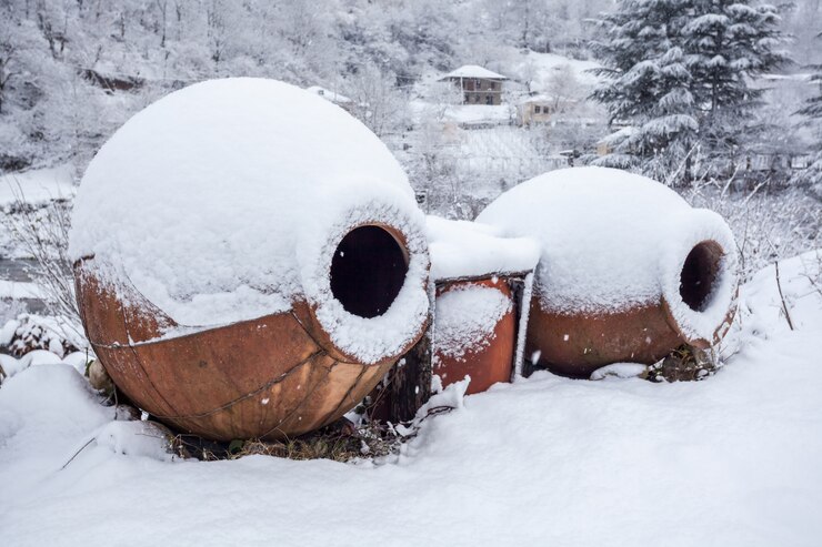 Photo snow covered georgian jugs for wine, outdoor in winter