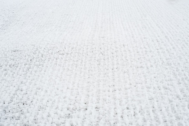 雪に覆われたグリッド。格子フェンスは新雪で覆われています。冬の背景のテクスチャ。