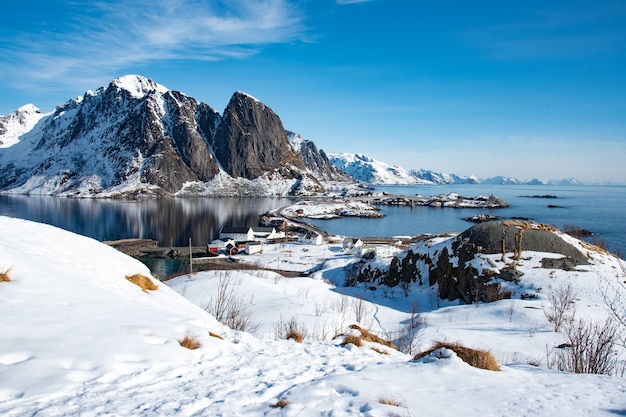 Snow covered hiking path with view of sea and snow capped mountain in blue sky day