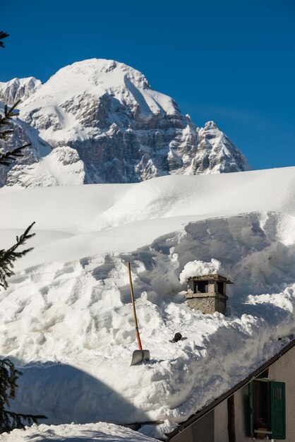 Snow covered house by mountain against clear blue sky