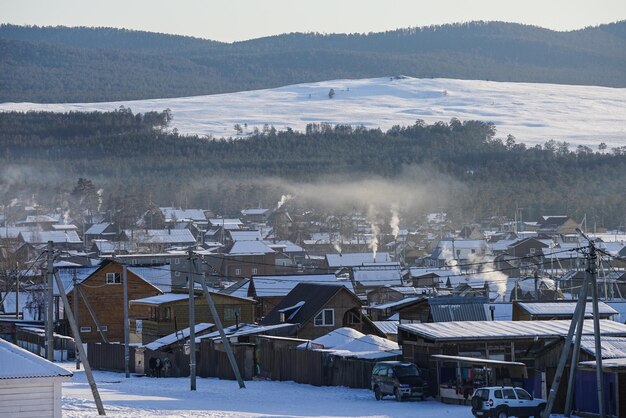 Photo snow covered houses by buildings against sky