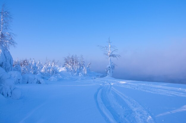 Snow covered land against clear blue sky