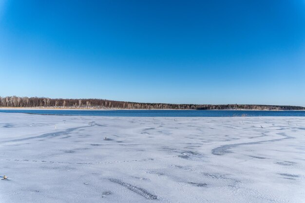 Snow covered landscape against clear blue sky