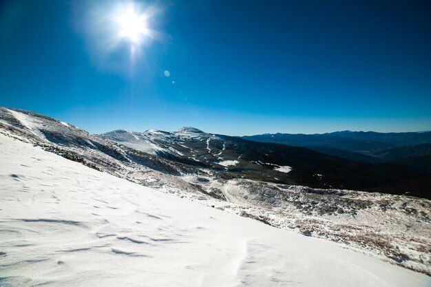 A snow covered mountain with a blue sky and sun shining on it