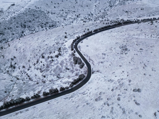 Snow covered mountains at sunset with a winding road in the foreground aerial view