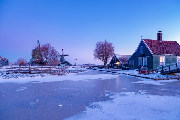 Snow covered road by buildings against clear blue sky