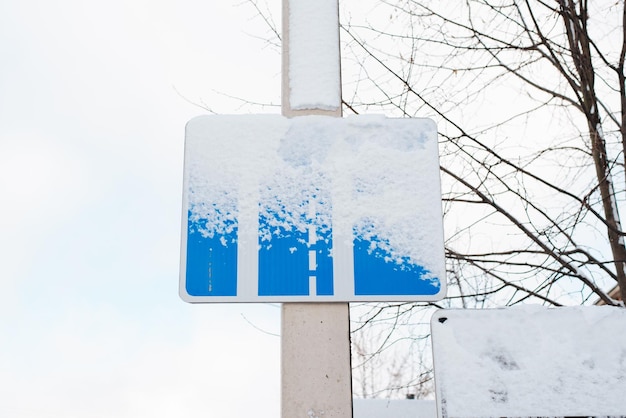 Snow covered road sign on a pole