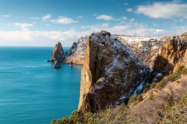 Заснеженные скалистые скалы над морем зимний закат над морем залив можжевельник под снегом концепции